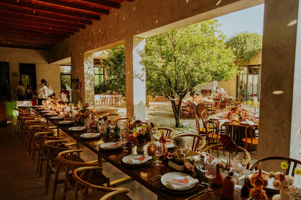 Charming outdoor wedding reception featuring long tables with floral centerpieces under open sky.