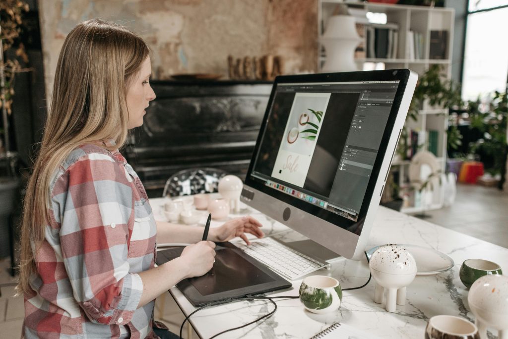 Woman using a digital drawing tablet in a stylish office workspace, focused on graphic design.